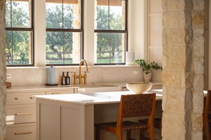 A kitchen with a large island, a sink, and a window with a view of greenery.