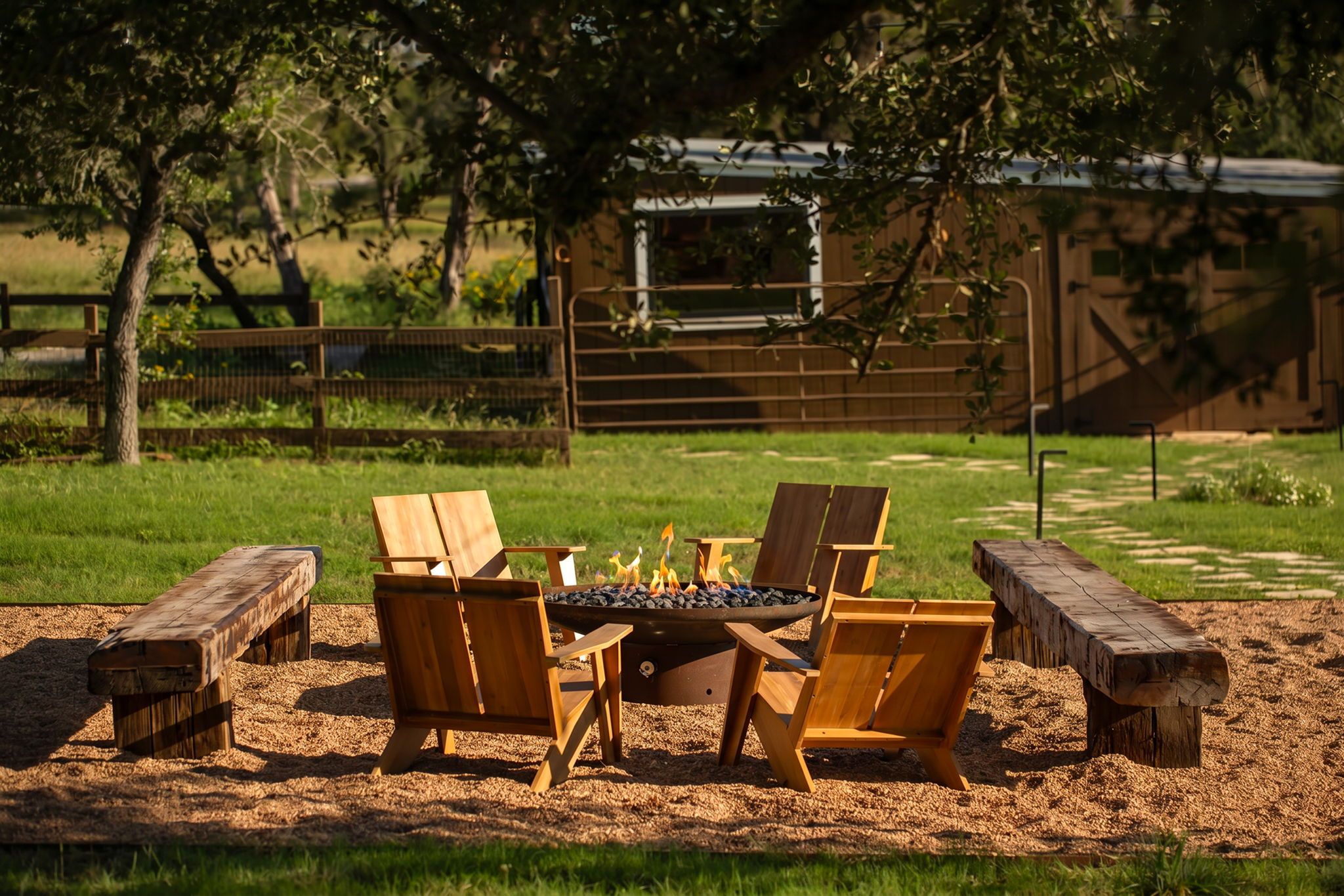 An outdoor seating area with a fire pit, wooden chairs, and benches.