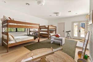 A room with bunk beds, a telescope, a small table, and a painting.