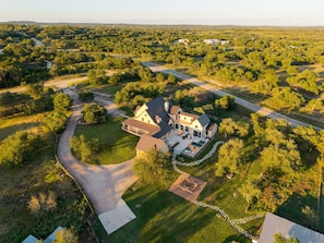 A large house with a spacious patio, a swimming pool, and a well-maintained lawn.
