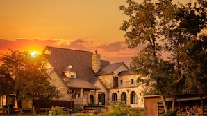 A stone building with a sloped roof, arched windows, and a chimney. - Deep Eddy Ranch (Dripping Springs)