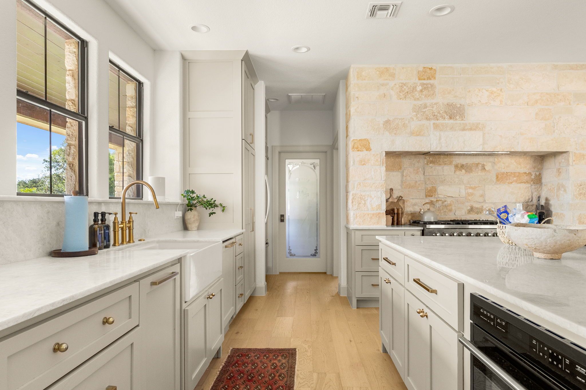 A kitchen with white cabinetry, a stone backsplash, and a view through a glass door.