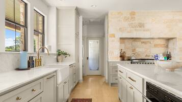 A kitchen with white cabinetry, a stone backsplash, and a view through a glass door.