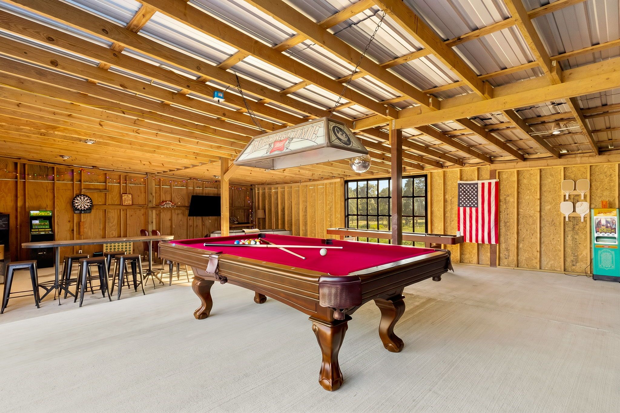 A pool table in a room with wooden walls and a high ceiling.
