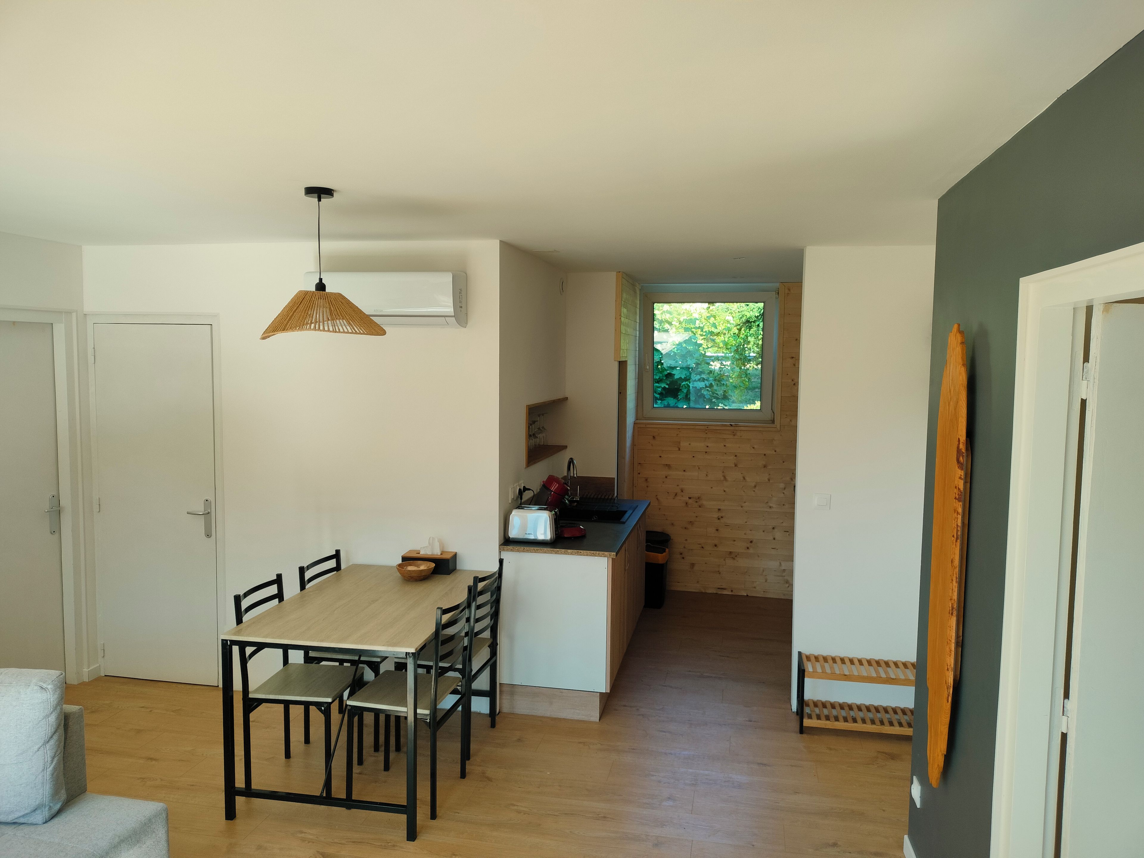 Une cuisine de taille réduite avec une fenêtre, un coin repas comprenant une table et des chaises, et un plancher en bois.