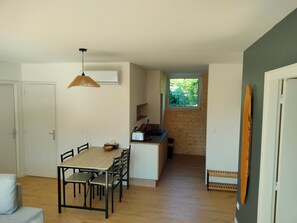 Eine kompakte Küche mit Fenster, ein Essbereich mit Tisch und Stühlen sowie ein Holzboden.