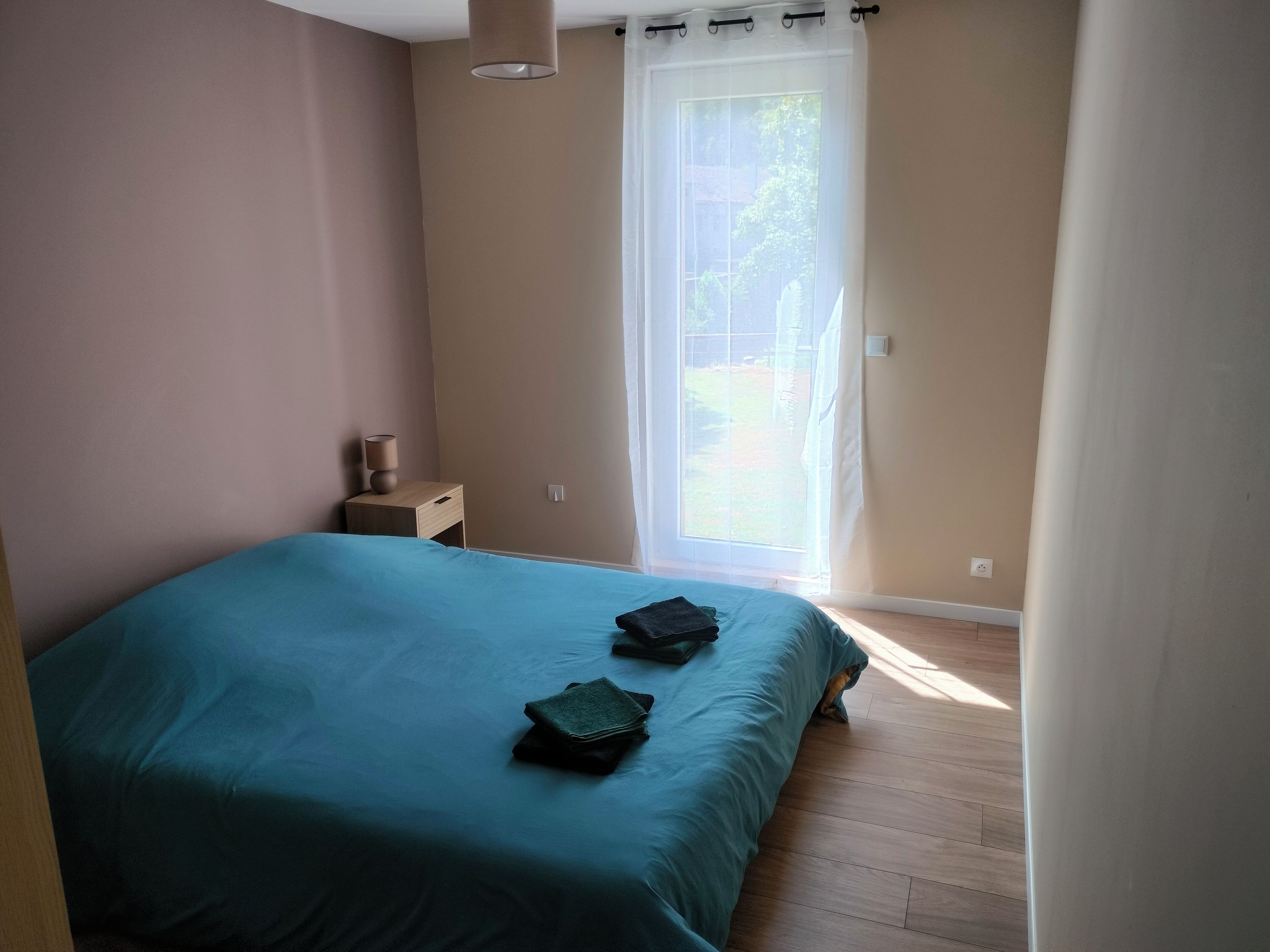 Une chambre à coucher avec un lit, une table de chevet et une fenêtre avec des rideaux.
