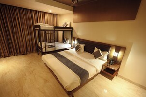 A hotel room with a bunk bed, a bedside table with a phone, and a curtain.