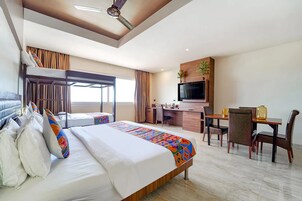Una habitación de hotel con cama, escritorio, silla, televisor y balcón.