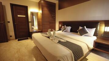 Quarto de hotel com uma cama grande, guarda-roupa de madeira e mesa de cabeceira com telefone.