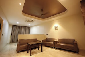 A modern living room with two leather sofas, a wooden coffee table, and a ceiling fan.