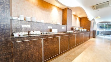 Um balcão extenso com diversos alimentos e utensílios, uma parede com padrão texturizado e um design de teto moderno.