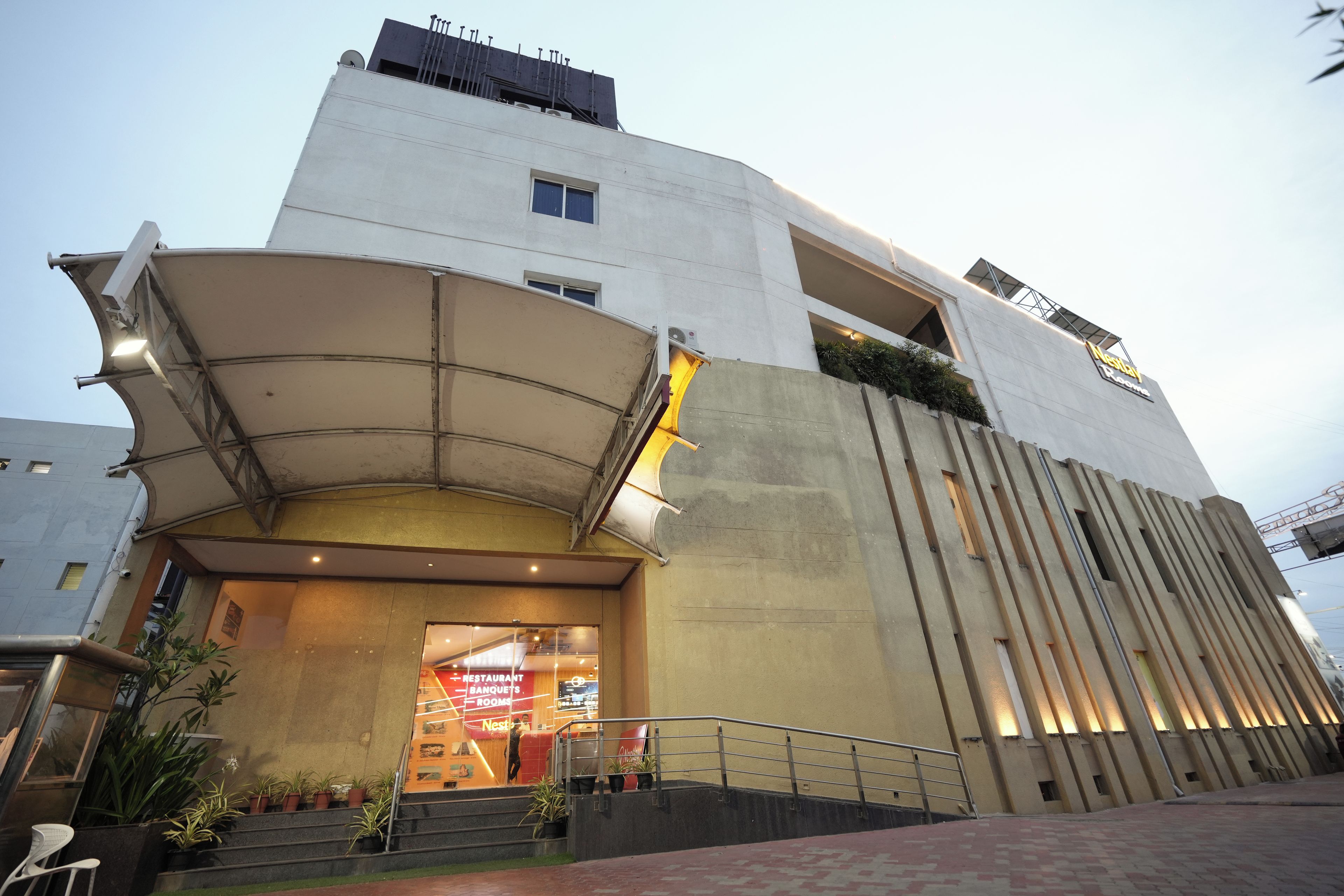 A modern building with a curved entrance, a staircase leading to the entrance, and a sign indicating a restaurant and banquet rooms.