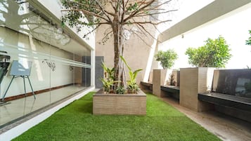 A modern outdoor area with artificial grass, a tree, and planters.