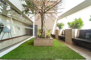 A modern outdoor area with artificial grass, a tree, and planters.