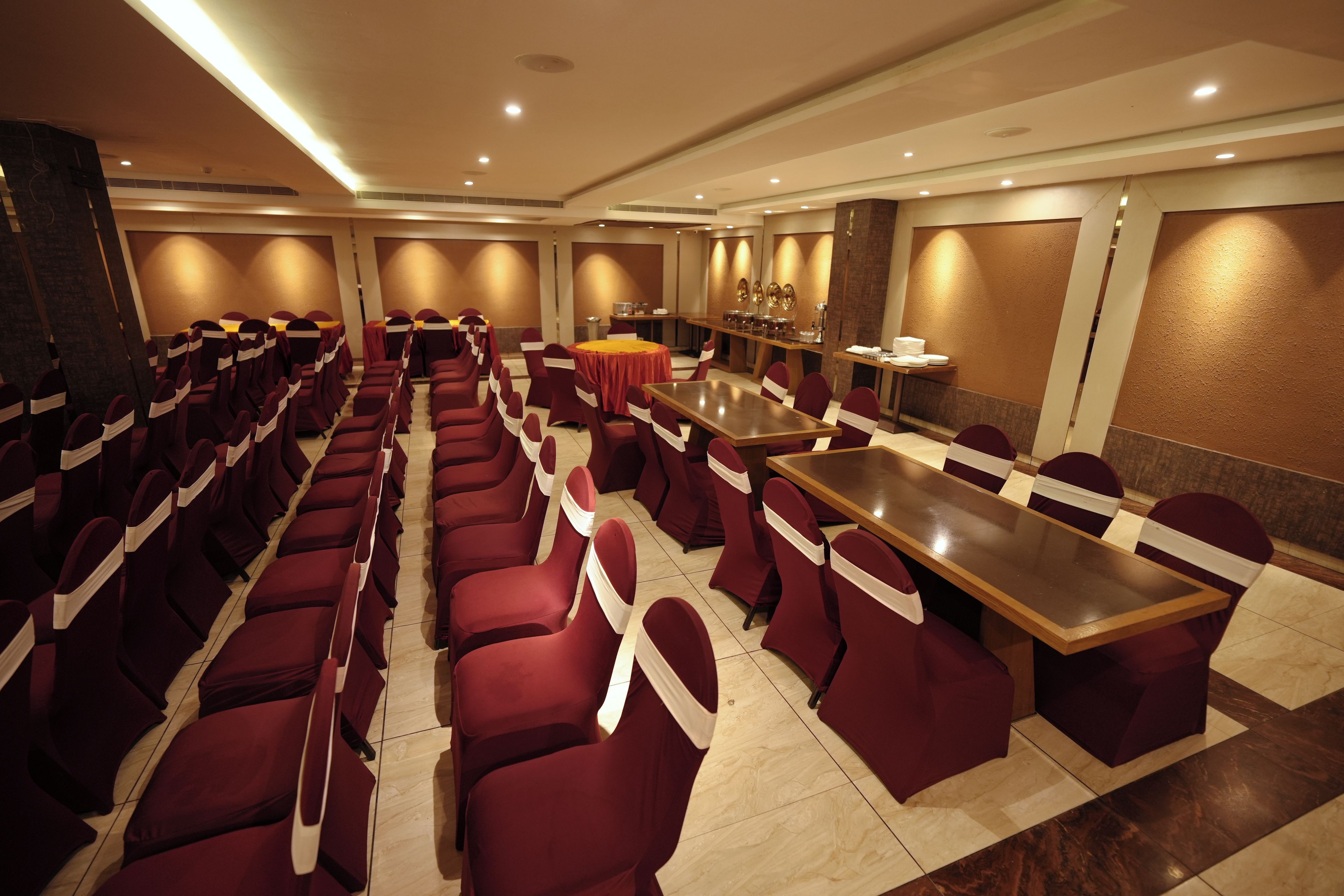 A conference room with rows of chairs and tables, equipped with ceiling lights and a sound system.