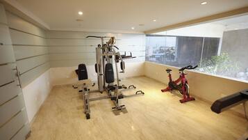 A gym with exercise equipment, a window with a view, and a tiled floor.