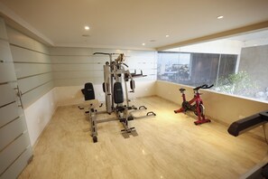 Un gimnasio con equipo de ejercicio, una ventana con vistas y un suelo de baldosas.