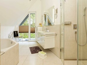 Ein modernes Badezimmer mit Duschkabine aus Glas, einer Badewanne und einem Waschtisch mit Spiegel.