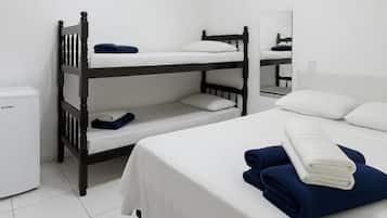 A room with bunk beds, a small desk, a mirror, and a white tiled floor.
