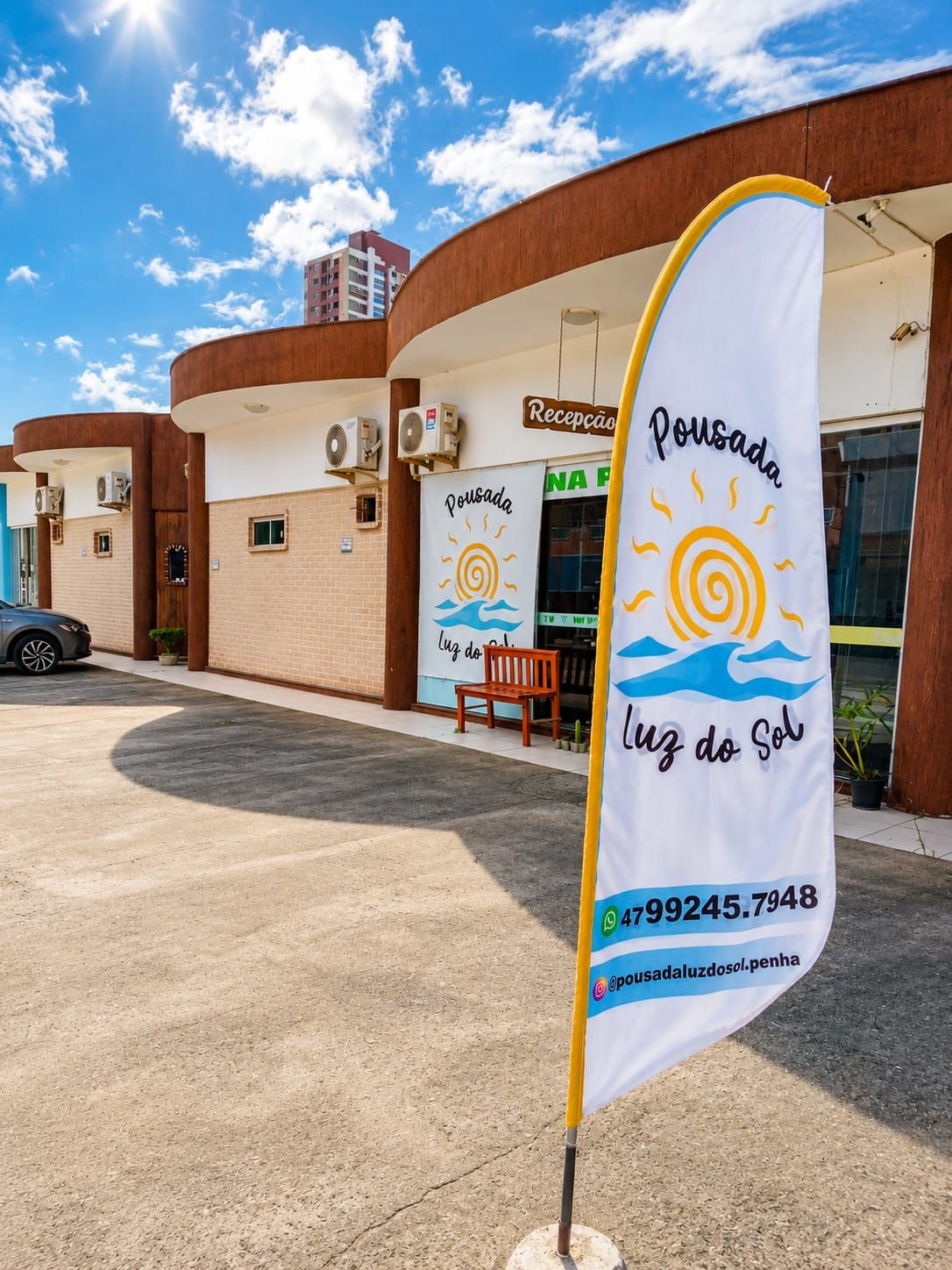 A building with a reception area, a flag with a sun and waves design, and a contact number.