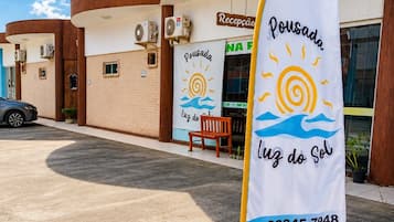 A building with a reception area, a flag with a sun and waves design, and a contact number.
