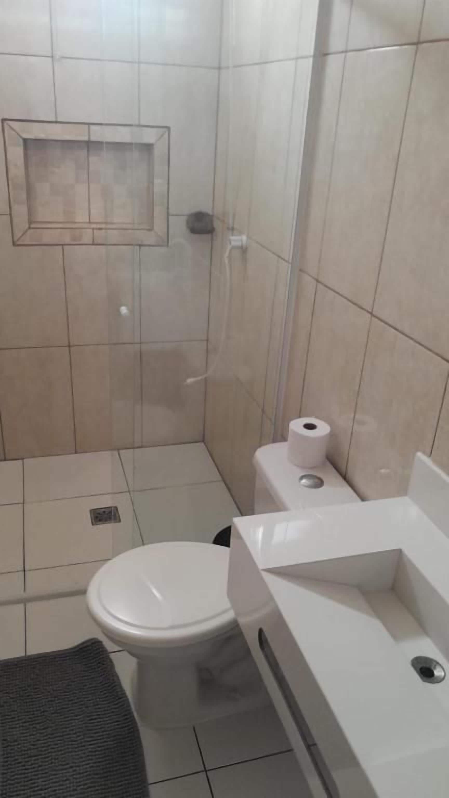 Un baño pequeño con azulejos, un inodoro, un lavabo y una cabina de ducha.