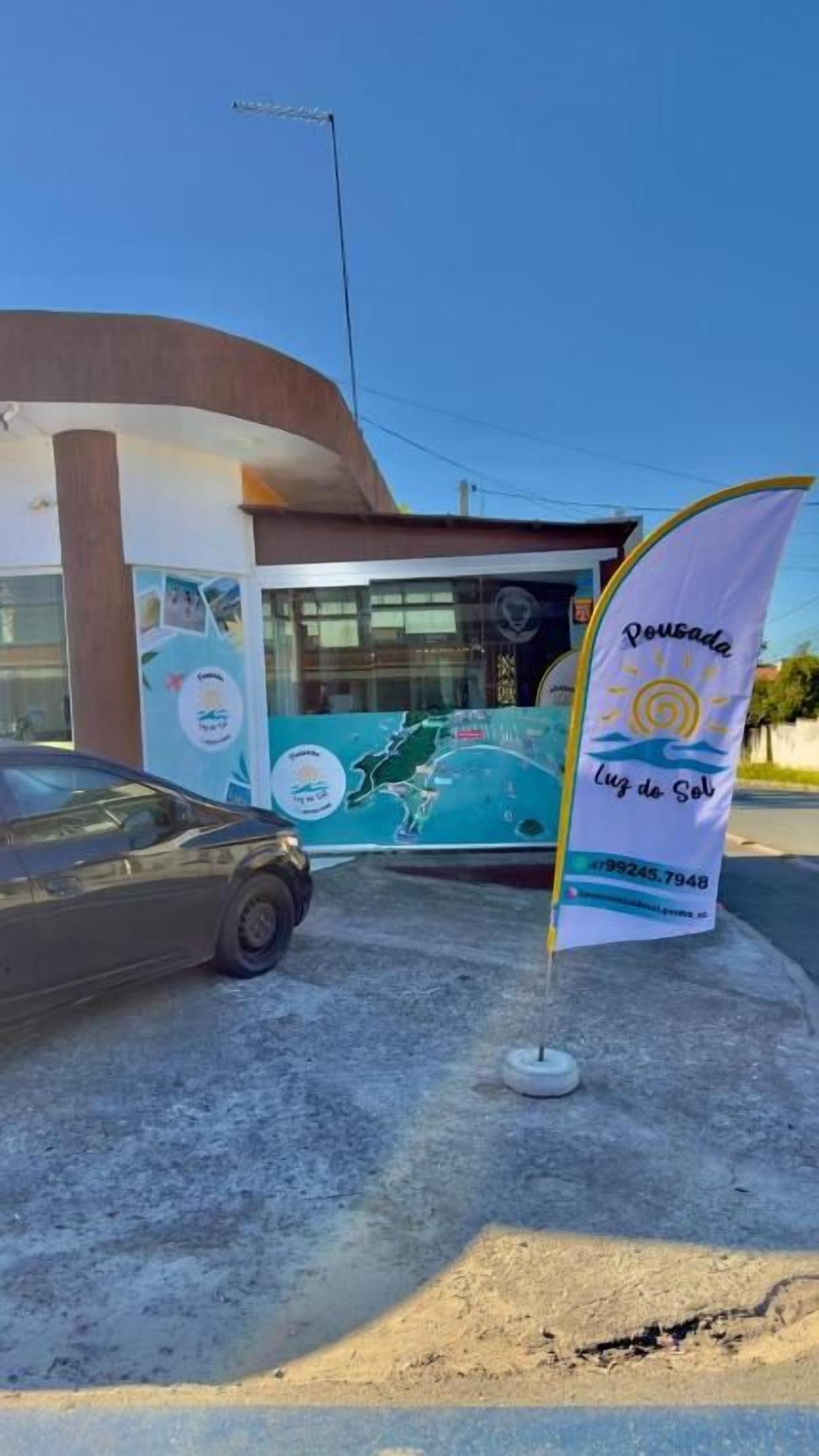A building with a modern design, a car parked in front, and a flag with text.