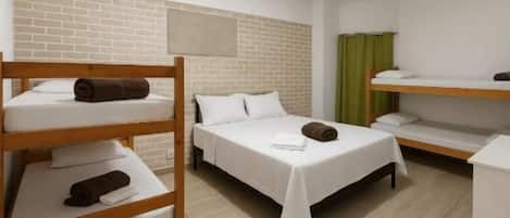 A room with bunk beds, a white bed, a brick wall, a green curtain, and a white ceiling.