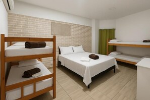 A hotel room with bunk beds, a brick accent wall, a green curtain, and a white bedside table. - Pousada Luz do Sol (Penha)