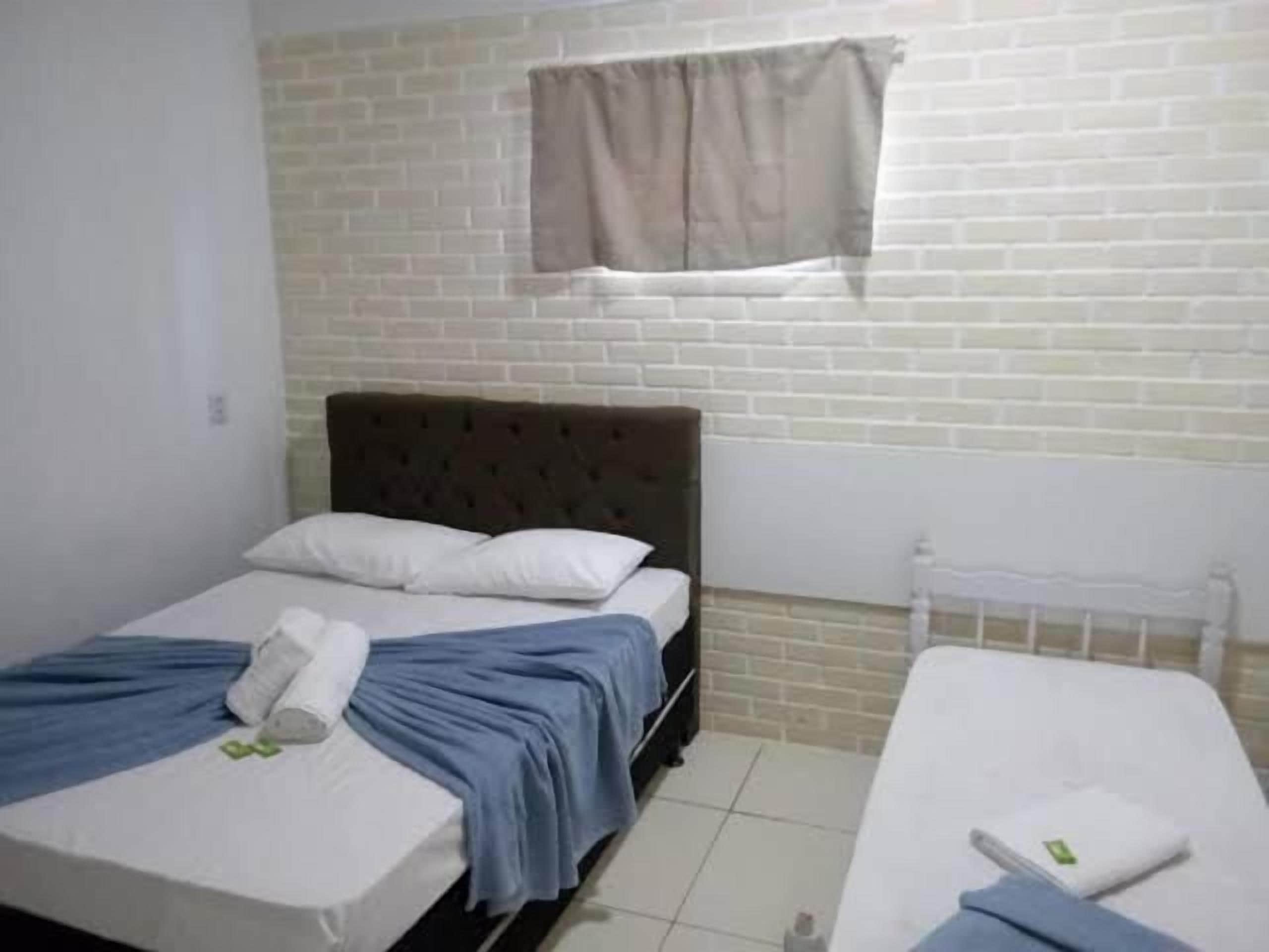 Una habitación con una cama, una mesita y un ventanal con cortinas.