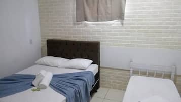 Una habitación con una cama, una mesita y un ventanal con cortinas.