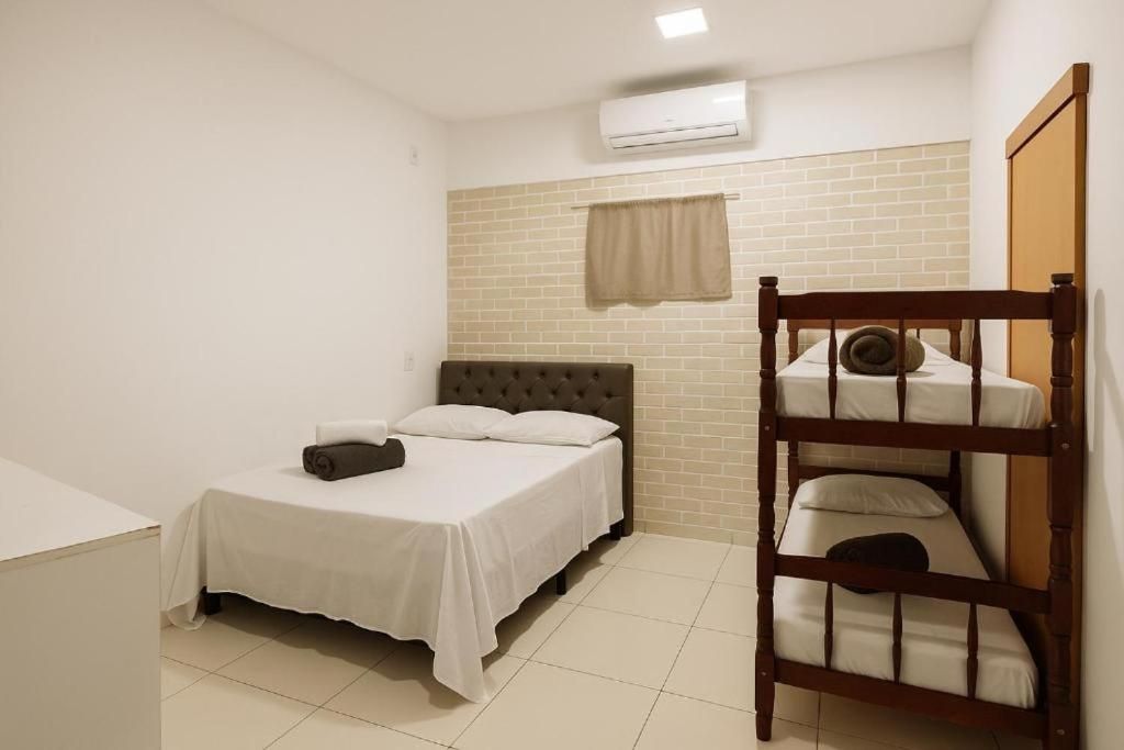 A bedroom with a single bed, a bunk bed, a window with a curtain, and an air conditioning unit.