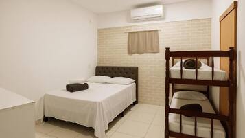 A bedroom with a single bed, a bunk bed, a window with a curtain, and an air conditioning unit.