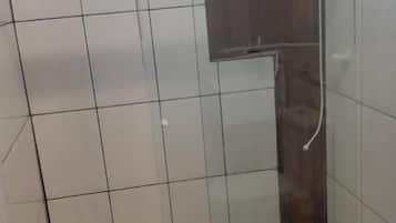 A glass-enclosed shower area with a tiled floor and a small shelf.