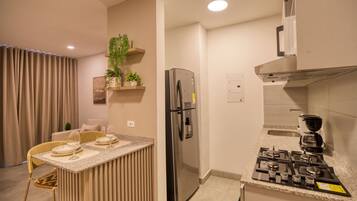 Une cuisine moderne dotée d’une cuisinière à gaz intégrée, d’un réfrigérateur en acier inoxydable et d’un coin bar avec des tabourets.