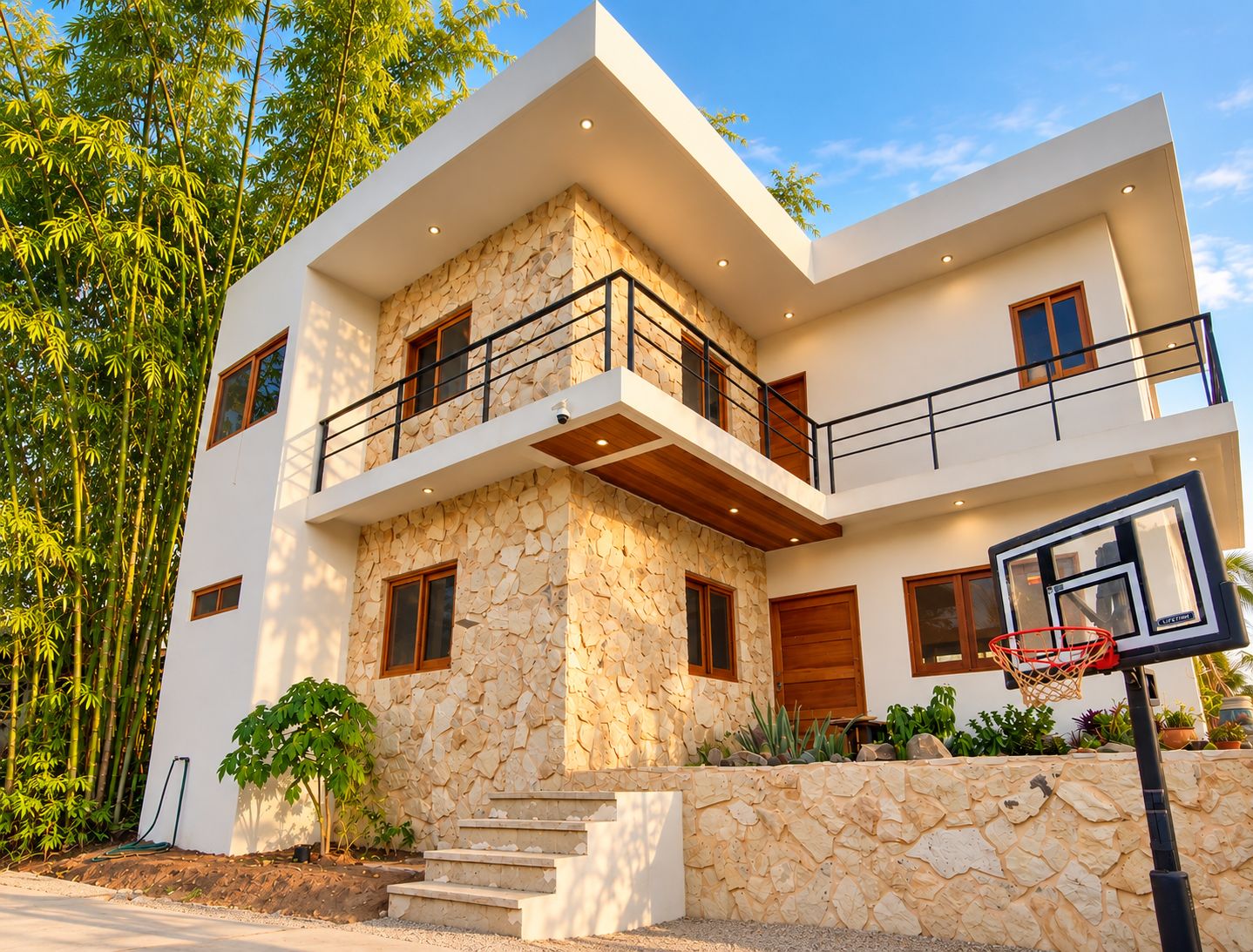 A modern two-story house with a stone facade, a balcony, and a basketball hoop.