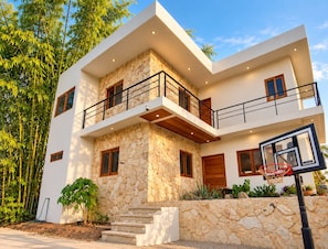 Een modern huis met twee verdiepingen, een stenen gevel, een balkon en een basketbalring.