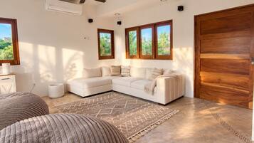 A modern living room with a sectional sofa, a patterned rug, and a wooden door.