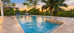 A swimming pool with a sunset view, surrounded by lush greenery and a fence. - Jungle Bliss Villa | Large Private Pool, Ocean Glimpses & Sunsets (Sayulita)