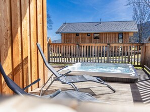 A wooden deck with a hot tub and lounge chairs. - One-bedroom Cabin (Sankt Georgen am Kreischberg)