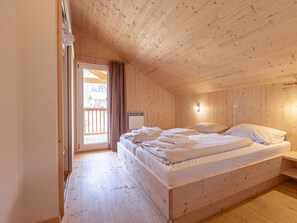 A wooden-paneled room with a bed, a window, and a door. - One-bedroom Cabin (Sankt Georgen am Kreischberg)