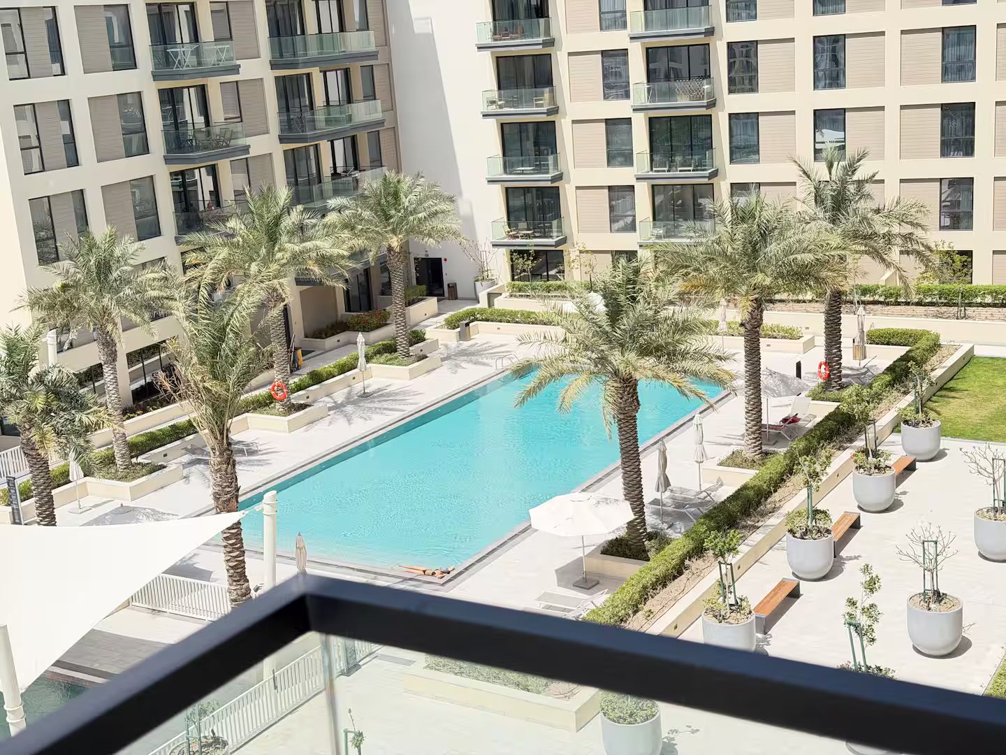 Un edificio moderno con piscina rodeada de palmeras y macetas.