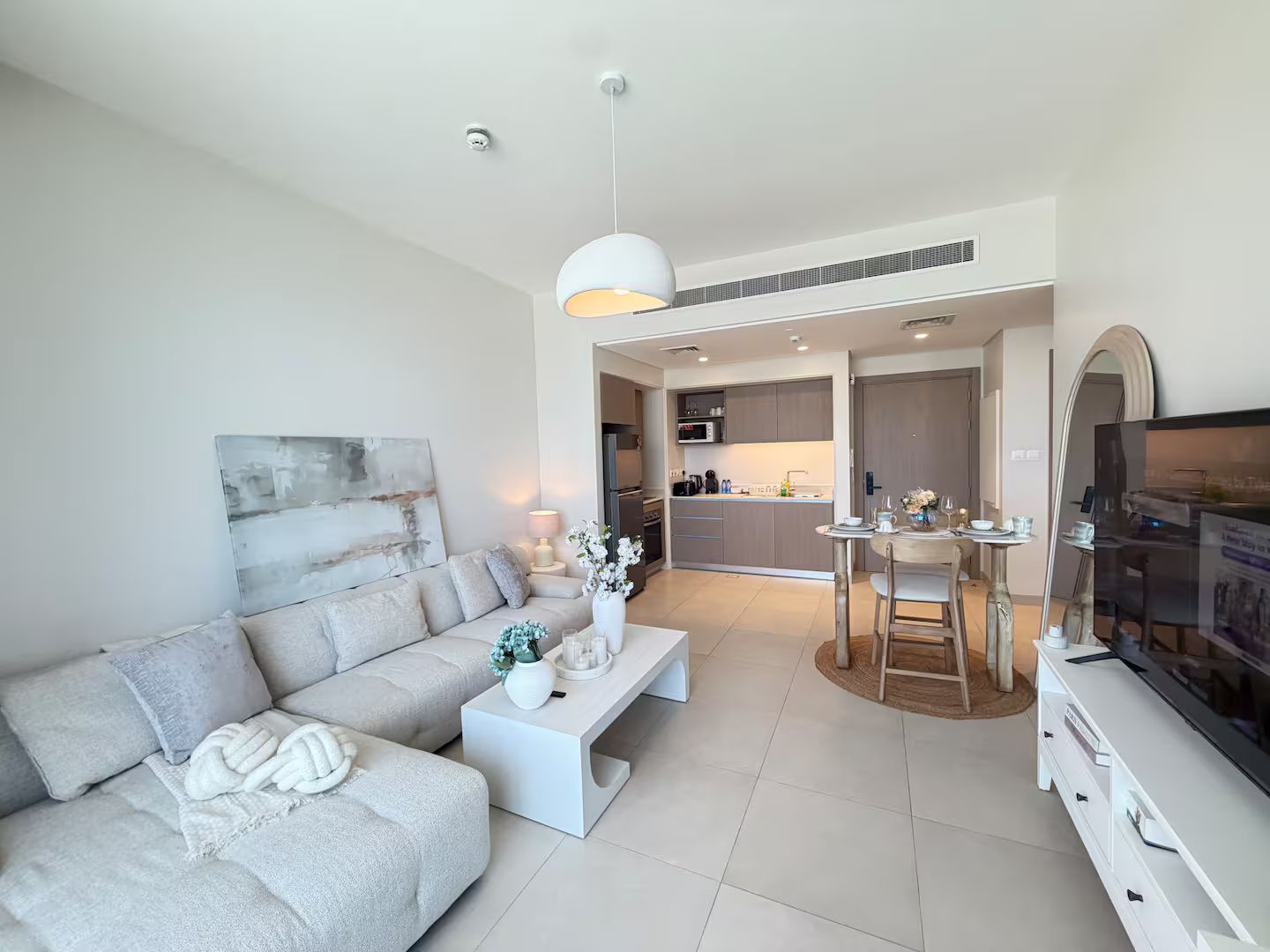 Una sala moderna con sofá, mesa de centro y televisión. Cuenta con una zona de cocina con mesa y sillas.