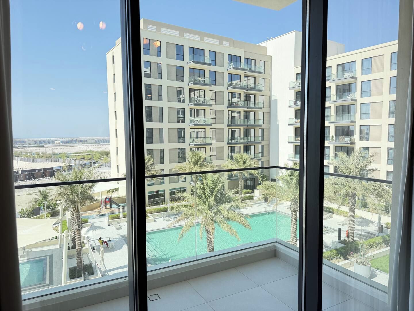 Un edificio alto con varios balcones, una piscina y una vista despejada del entorno.