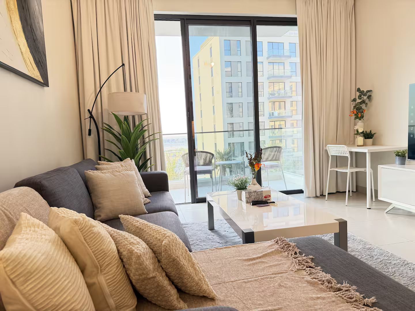 Una sala moderna con sofá, mesa de centro y vista a un paisaje urbano a través de amplios ventanales.
