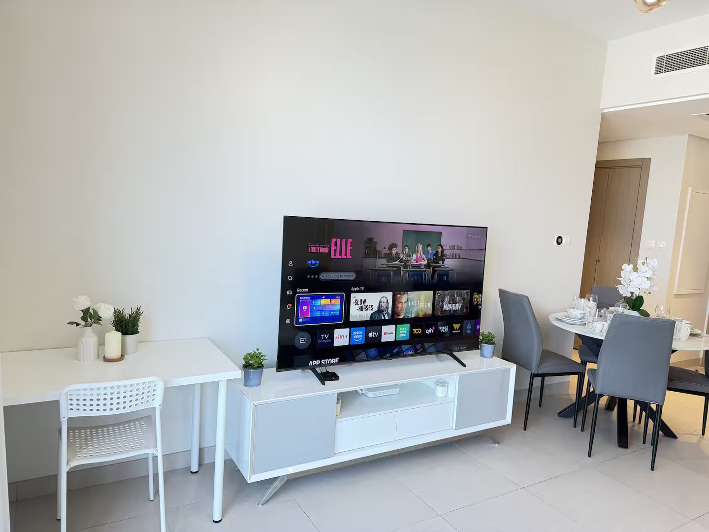 Una sala moderna con un televisor de pantalla plana montado en un mueble blanco.