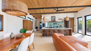 Eine moderne Küche mit einer zentralen Kochinsel, Barhocker und einem Essbereich mit Holztisch und Stühlen.