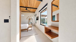Ein modernes Schlafzimmer mit Bett, Sitzbank, Spiegel und Fenster.