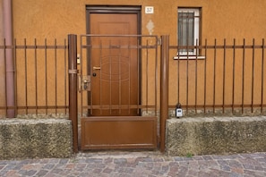 Ein verschlossener Eingangsbereich mit einer braunen Tür, einem Metallgitter und einem kleinen, vergitterten Fenster.